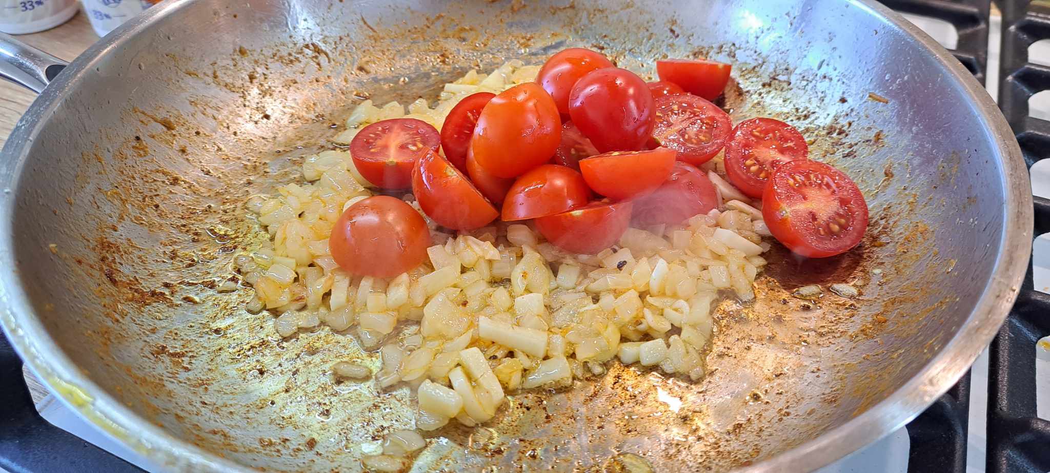 K cibuli s cesnakom pridáme rozkrojené cherry paradajky.